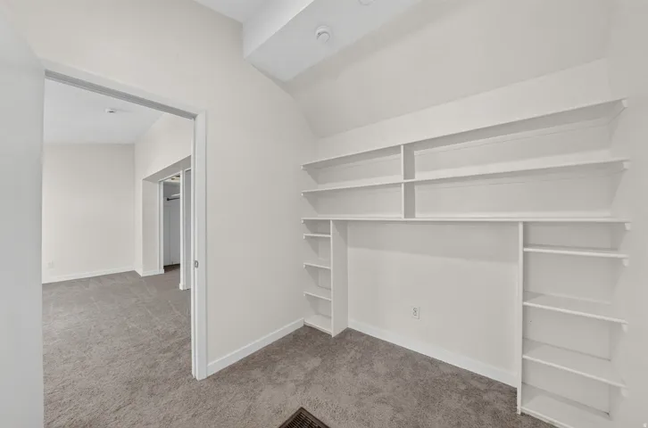 Built-in shelving, plush carpet flooring, recessed ceiling lighting, and crisp white wall finishes