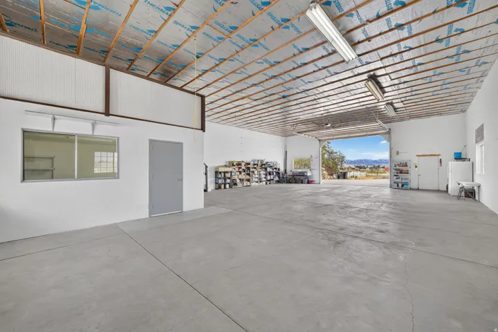 Expansive open-concept interior featuring concrete flooring, exposed ceiling beams, and integrated fluorescent lighting