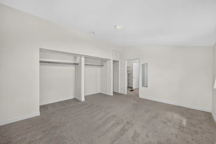 Plush gray carpet flooring, recessed ceiling lighting, and a built-in closet with hanging rods