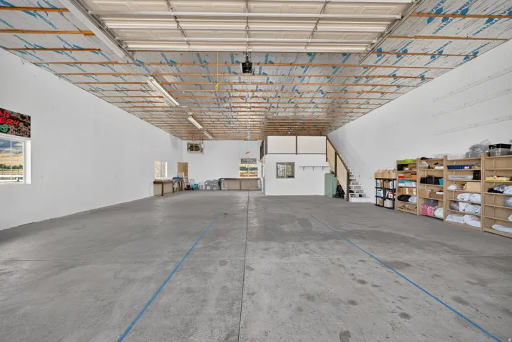 Expansive concrete flooring throughout, high ceilings with exposed wood beams, and a built-in mezzanine level