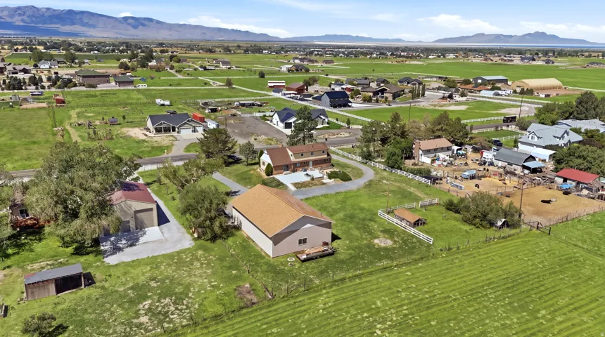 Expansive property featuring mature trees, multiple outbuildings, and a surrounding mountain landscape