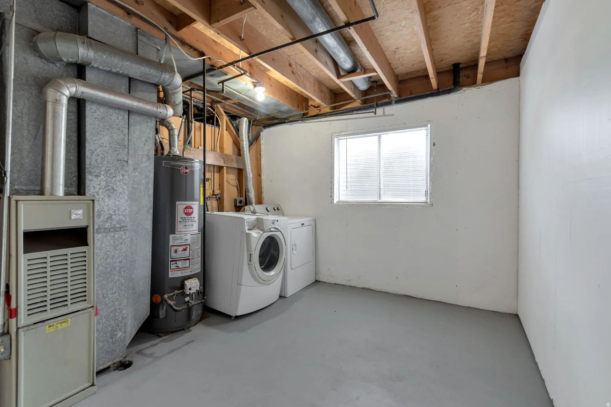 Laundry area with a washer and dryer, featuring a water heater, furnace, and a window