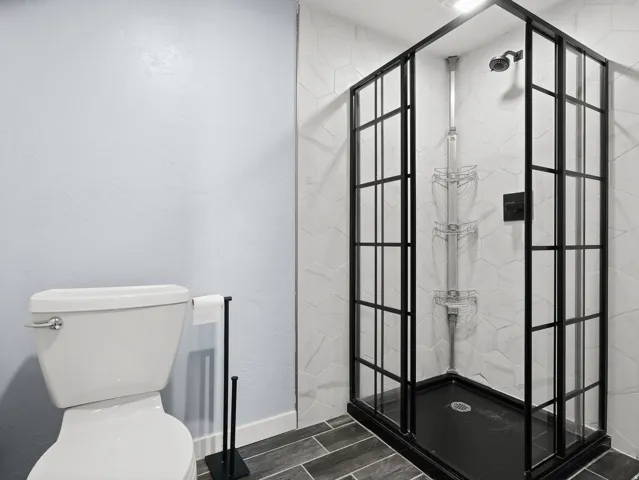 Enclosed shower with black frame, hexagonal wall tile, and dark shower base