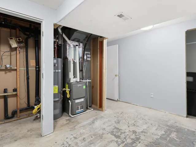 Exposed utilities, water heater, and furnace in a utilitarian space