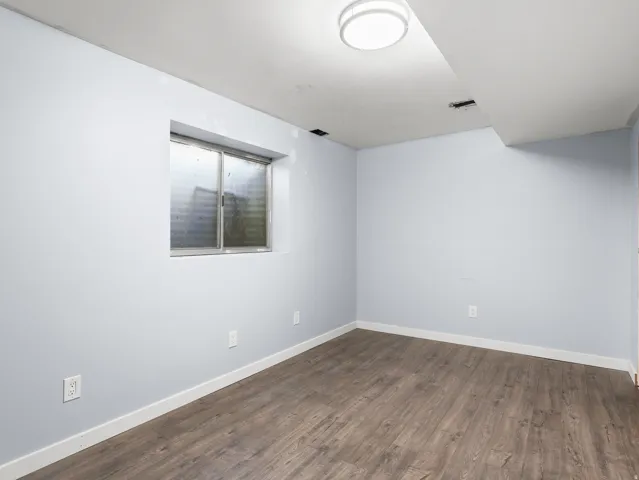 Room featuring wood-finish flooring, light-colored walls, a window, and a flush-mount ceiling light