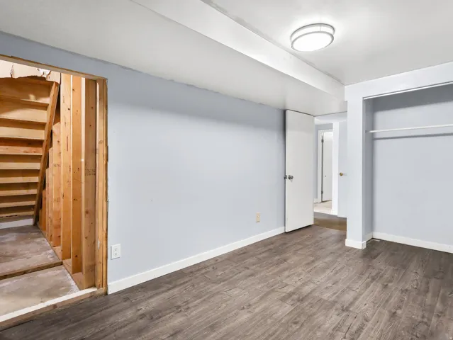 Wood-finish flooring throughout, light blue wall paint, white trim, and a flush mount ceiling light