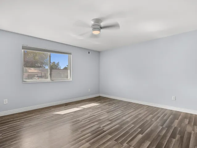 Wood-finish plank flooring, large window, ceiling-mounted light fixture, and white trim molding