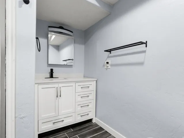 White vanity with multiple storage drawers and cabinet, light-toned countertop, and integrated sink