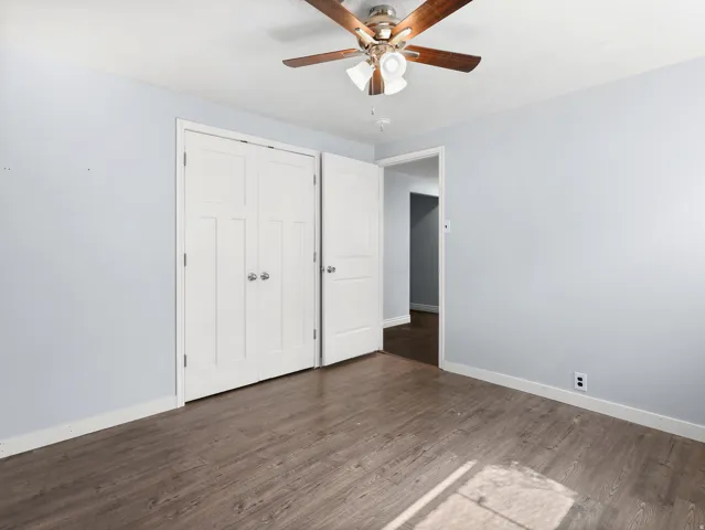 Wood-finish flooring, paneled closet doors, and a ceiling fan with integrated lighting