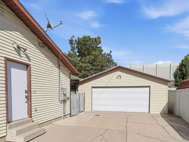 Detached garage with white overhead door, concrete driveway, and exterior lighting