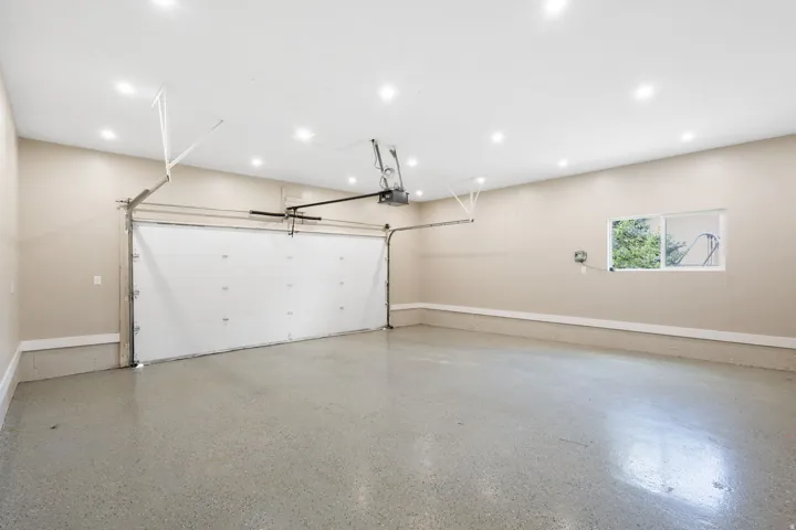Two-car garage with a roll-up door, recessed lighting, and a window