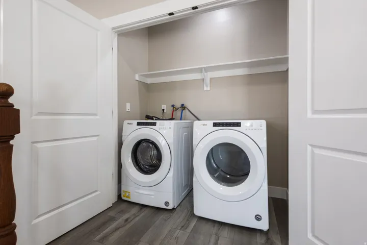 Dedicated laundry closet with wood-finish flooring and integrated shelving