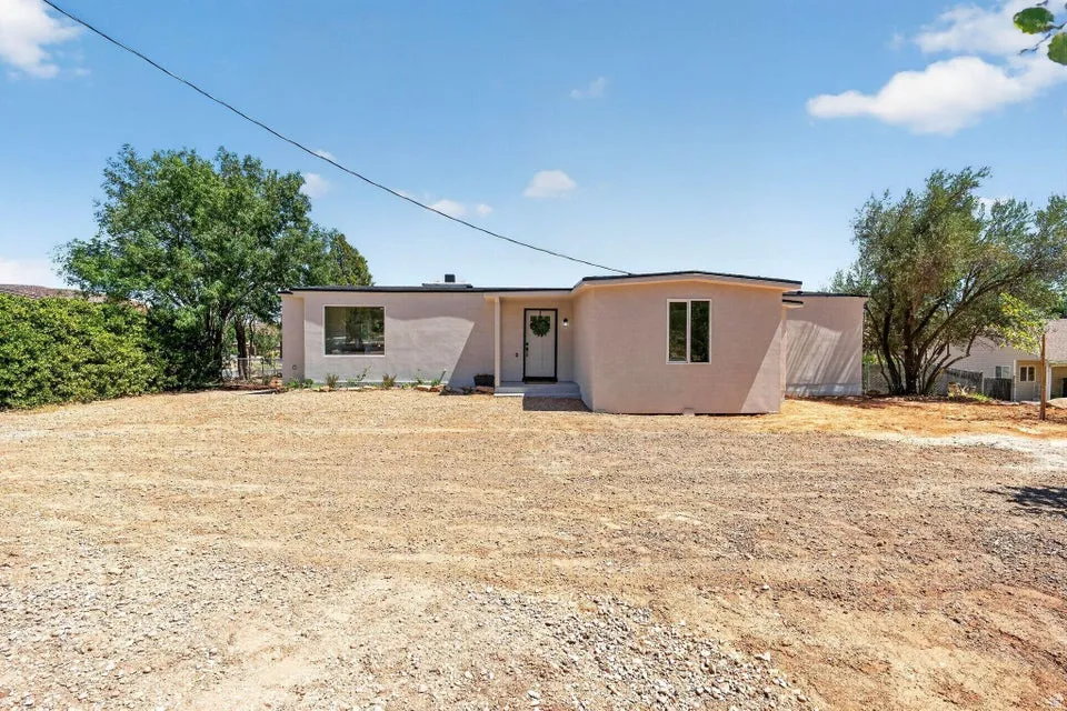 Smooth stucco exterior with a flat roofline, featuring black-framed windows and a central entry door with a wreath