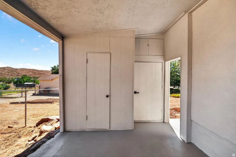 Covered outdoor space featuring a smooth concrete floor and two utility doors