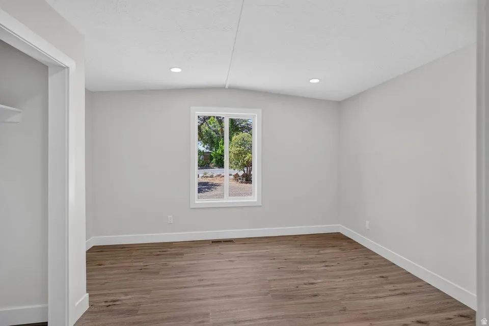Wood-finish flooring, recessed ceiling lighting, a large window, and white trim