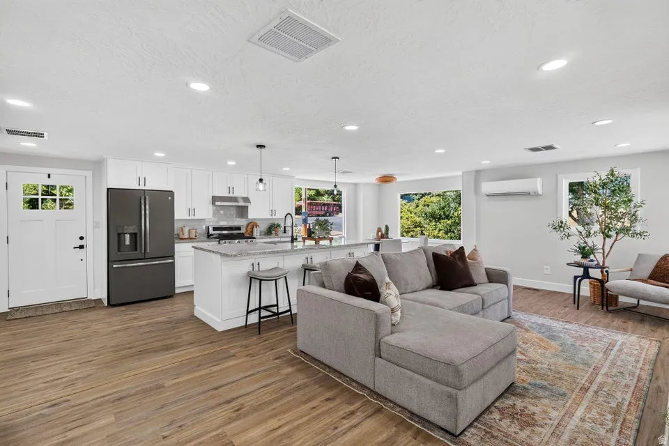 Open-concept living space with wood-finish flooring, recessed lighting, and white walls