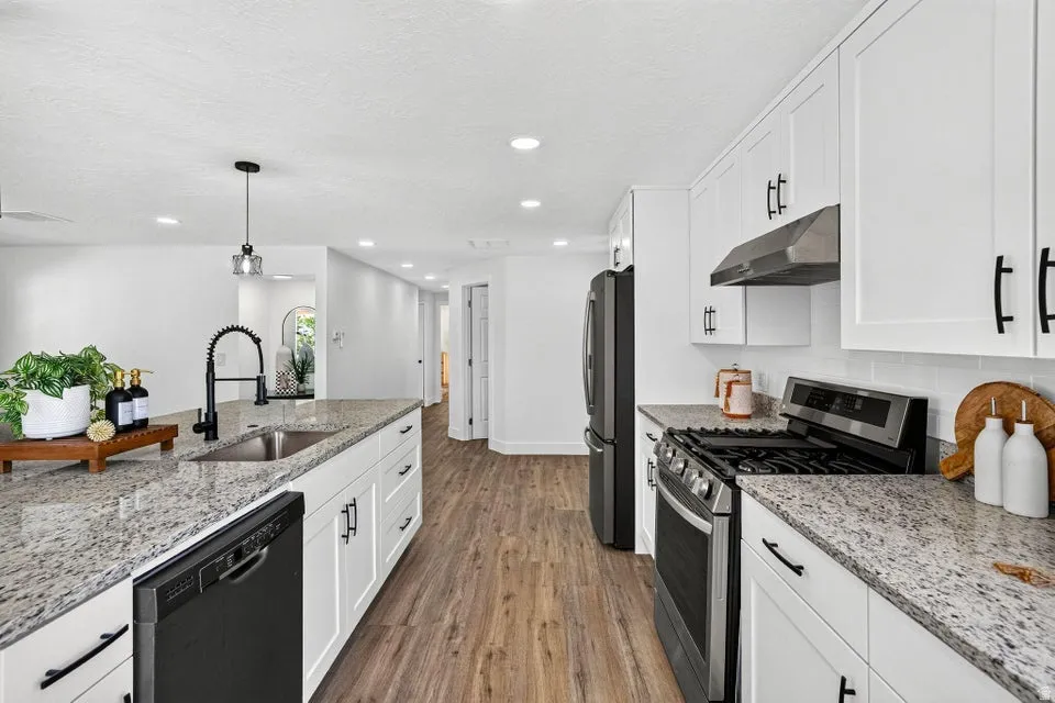 Kitchen featuring white cabinetry, stone countertops, stainless steel appliances, wood-finish flooring, and recessed lighting