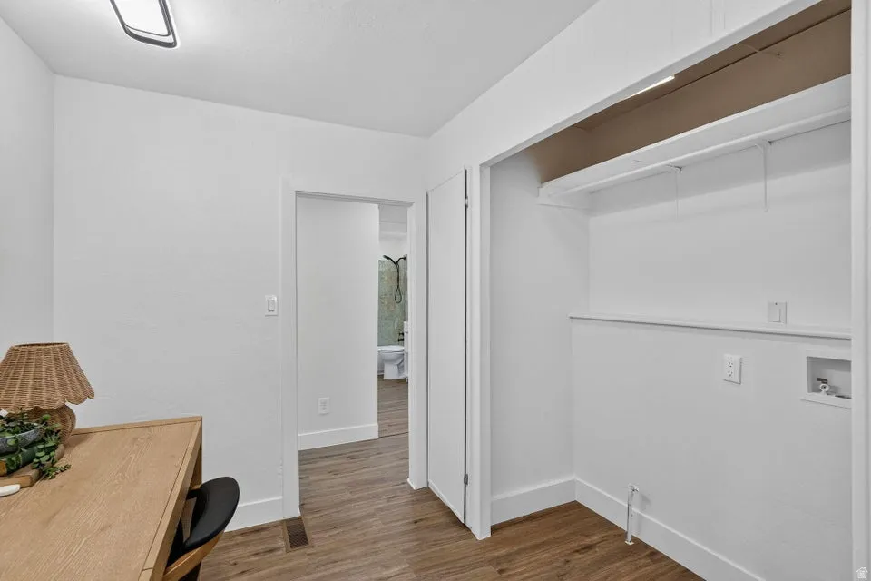 Recessed closet with integrated shelving, wood-finish flooring, and white wall finishes