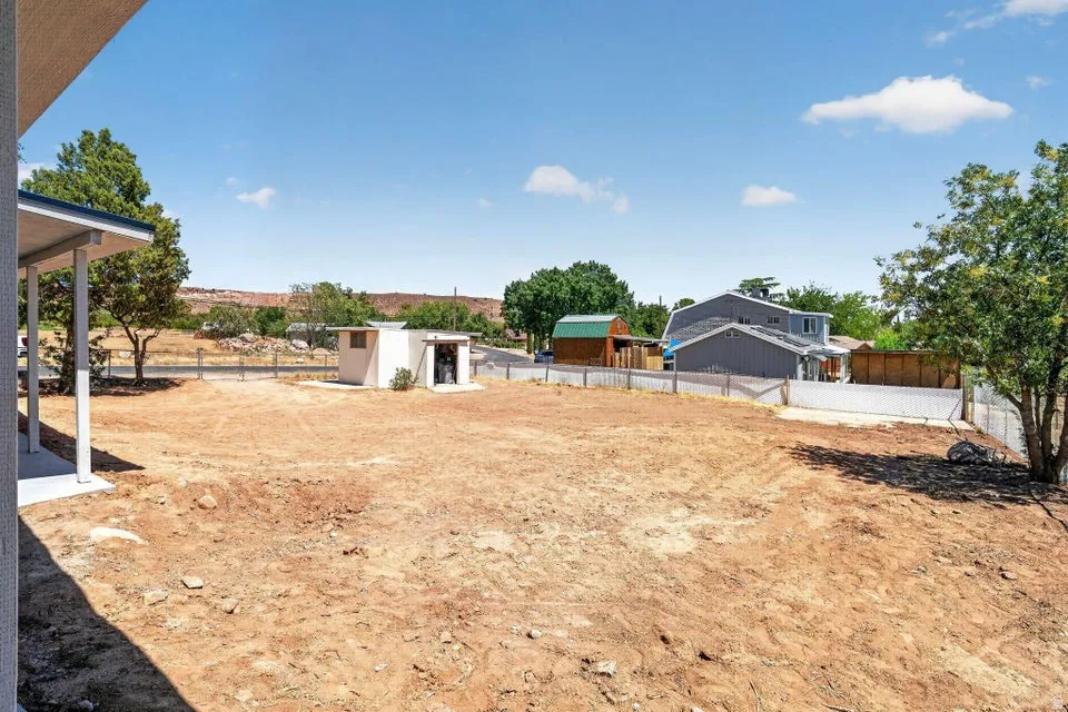 Expansive undeveloped lot featuring a concrete patio, white support columns, and a dedicated storage shed