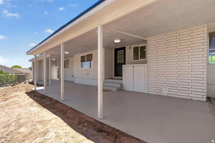 Expansive covered patio featuring a concrete surface, white brick accents, multiple windows, and a secure exterior door
