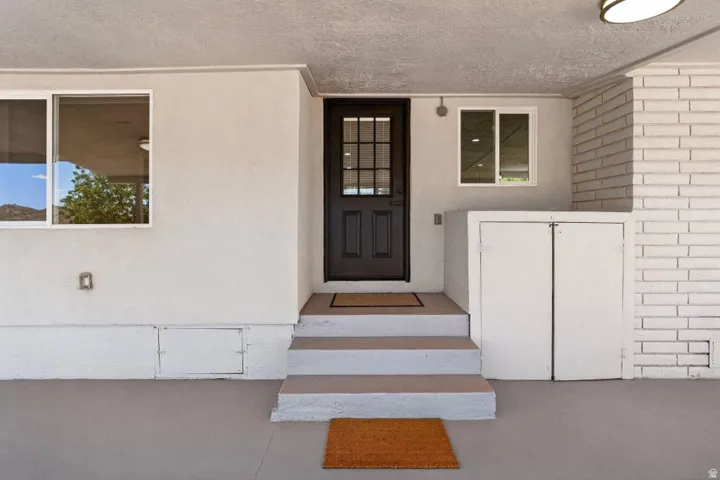 Entryway featuring a dark paneled door with glass inserts, white stucco exterior, and white brick column