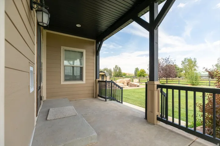 Covered concrete front porch with black railing and wood siding