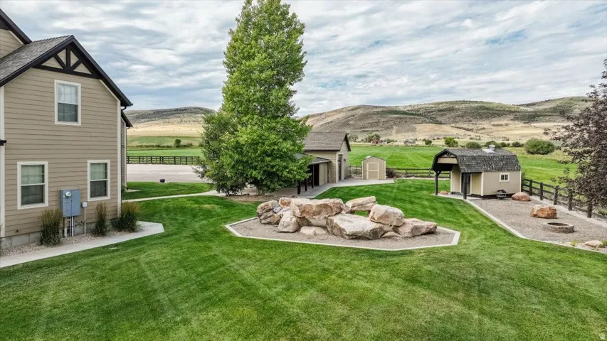 Expansive landscaped grounds with a large lawn, decorative rock features, and a fire pit