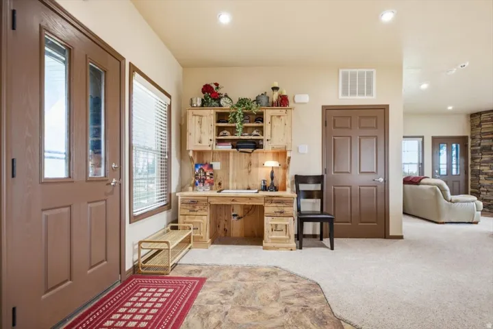 Entryway featuring a paneled door with glass inserts, recessed lighting, and a built-in wood-finish desk