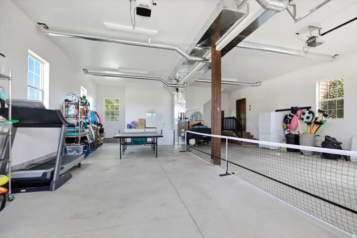Spacious utility room with exposed ductwork, concrete flooring, and multiple windows