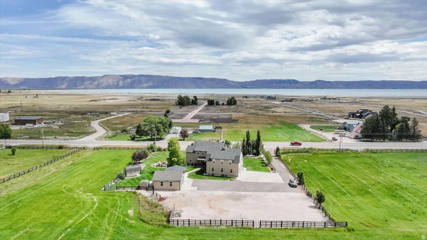 Expansive property featuring a multi-story residence, a detached auxiliary building, and a large gravel parking area