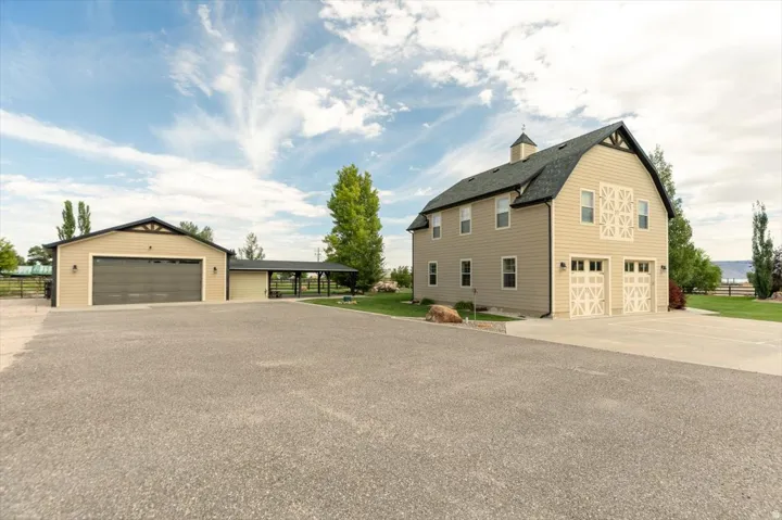 Two-story barn-style structure with dual garage doors, a cupola, and adjacent detached garage with covered walkway
