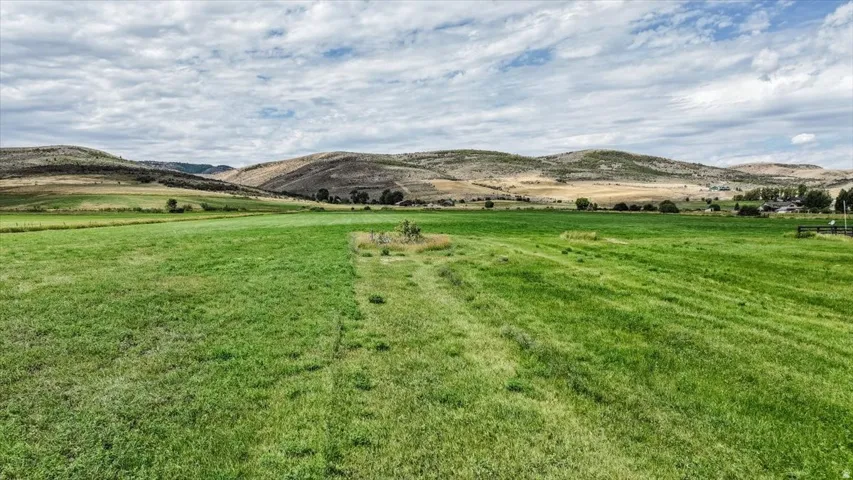 Expansive green field with distant rolling hills and a partially visible structure