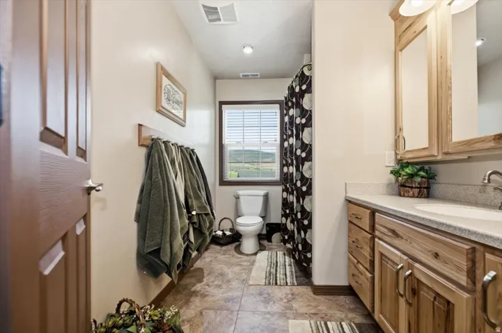 Bathroom featuring a single vanity with wood-finish cabinetry, a toilet, a shower/tub combination, and tiled flooring