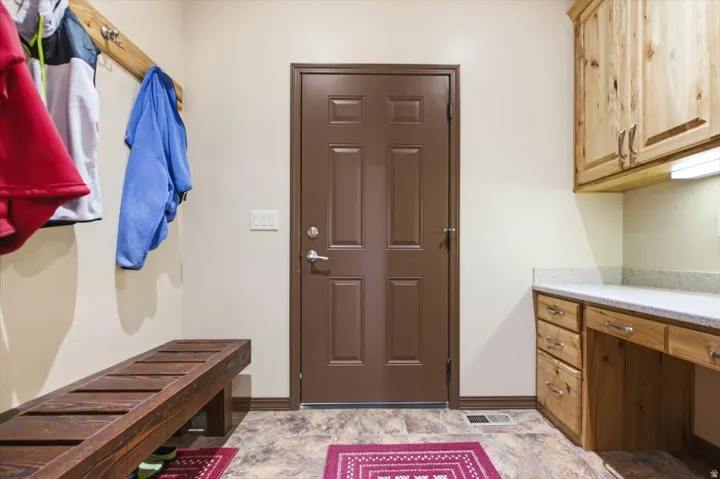 Built-in wooden bench, wood-finish flooring, paneled door, built-in wooden cabinetry, and stone-finish countertop