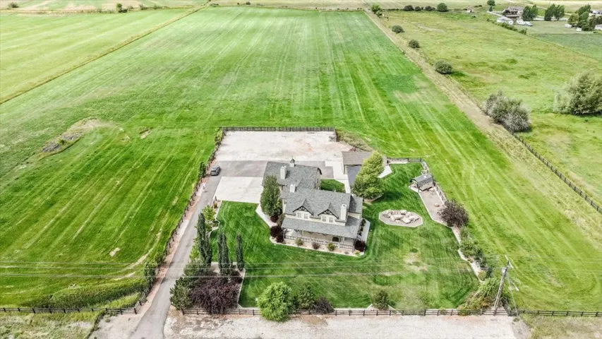 Expansive property featuring a two-story residence with a gray shingle roof, a large paved driveway, and manicured lawns