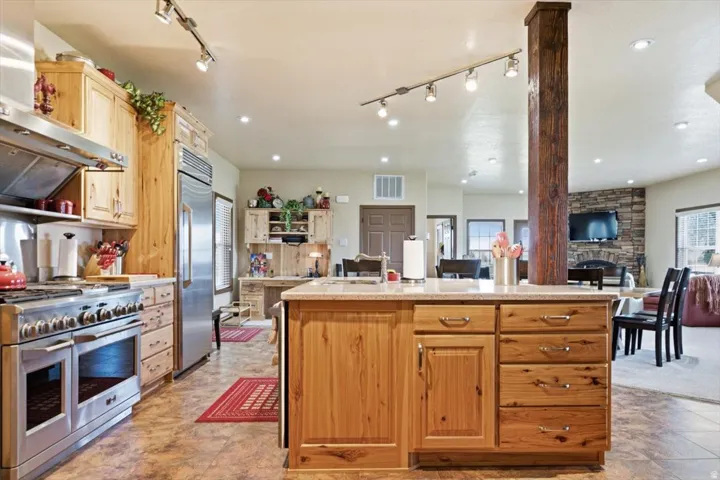 Kitchen featuring wood cabinetry, stainless steel appliances, a center island with a stone-look countertop, track lighting, and recessed lighting