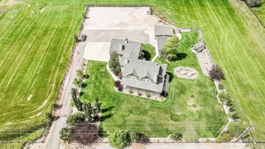 Spacious property featuring a large residence, expansive green lawns, a paved driveway, and a gravel-surfaced area