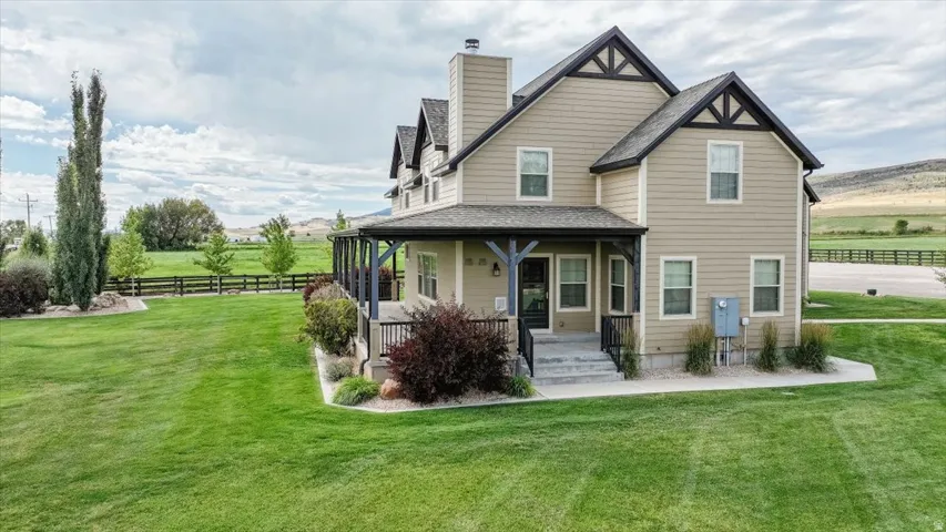 Two-story residence featuring siding exterior, covered porch with dark wood accents, and a prominent chimney