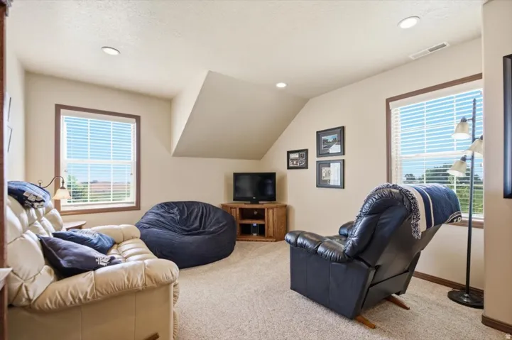 Recessed ceiling lighting, sloped ceiling detail, and two windows with blinds