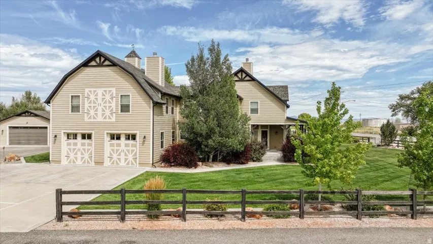 Gable roofline, board-and-batten siding, attached two-car garage, separate detached garage, and a expansive manicured lawn
