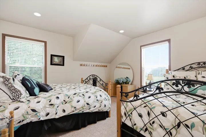 Room with sloped ceiling, recessed lighting, and two windows featuring blinds