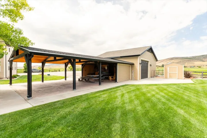 Detached three-car garage with a covered outdoor entertaining area, featuring a pitched roof and a separate storage shed
