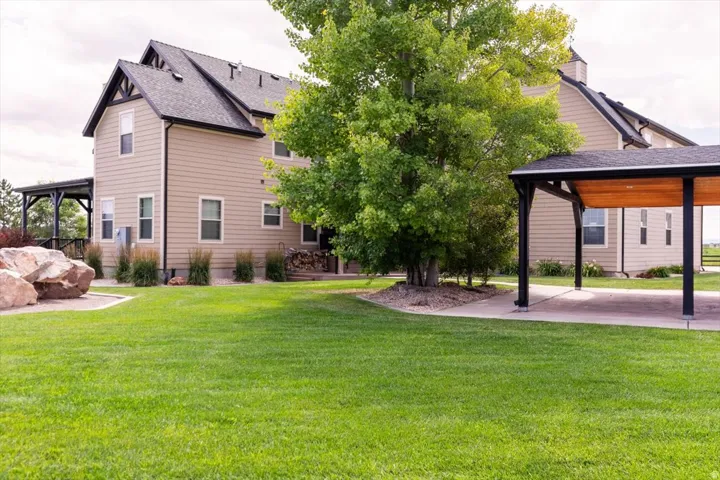Two-story exterior with siding, covered patio, carport with wood-finish ceiling, and expansive lawn