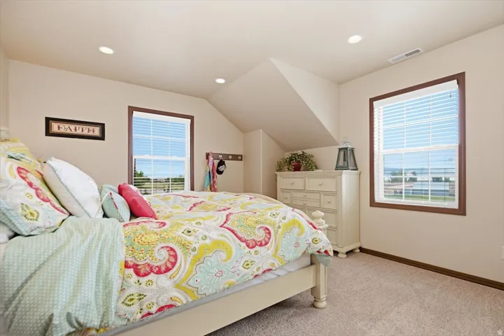 Recessed ceiling lighting, sloped ceiling detail, dual windows with blinds, wood-finish window trim, and wall-to-wall carpeting