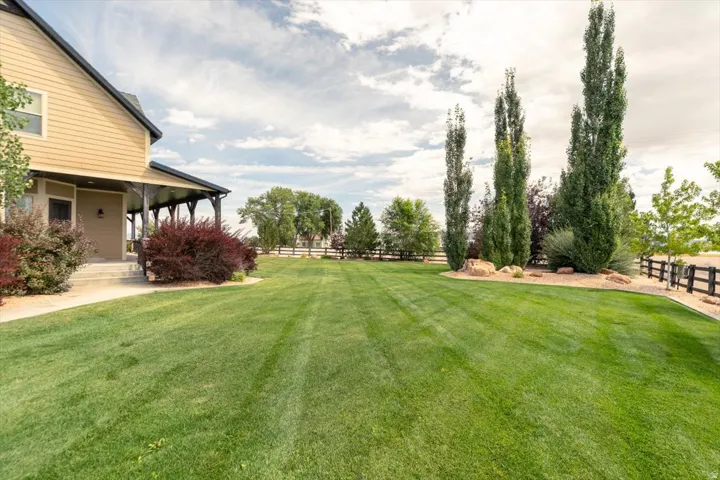 Expansive green lawn with established landscaping, featuring mature trees and decorative shrubs