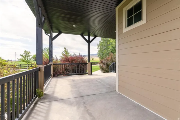 Covered porch featuring a concrete surface, dark wood posts, and black metal railings