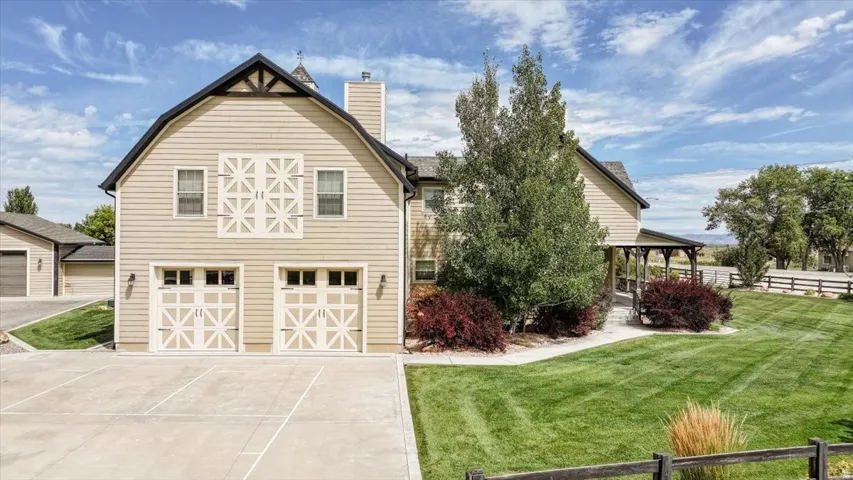 Barn-style exterior featuring a gambrel roofline, two-car garage, upper-level faux doors, and a covered porch