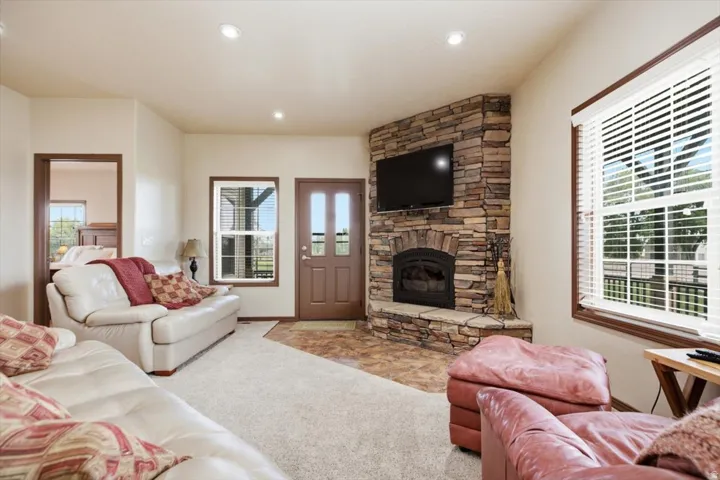 Corner stone fireplace with a hearth, recessed lighting, and a wood-finish entry door with glass panels