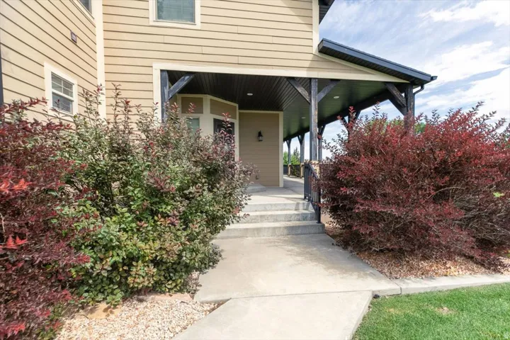Siding exterior, covered front porch with exposed beams, concrete walkway, and mature landscaping