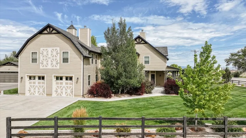 Two-story residence featuring gambrel rooflines, a two-car garage with decorative doors, and a covered front porch
